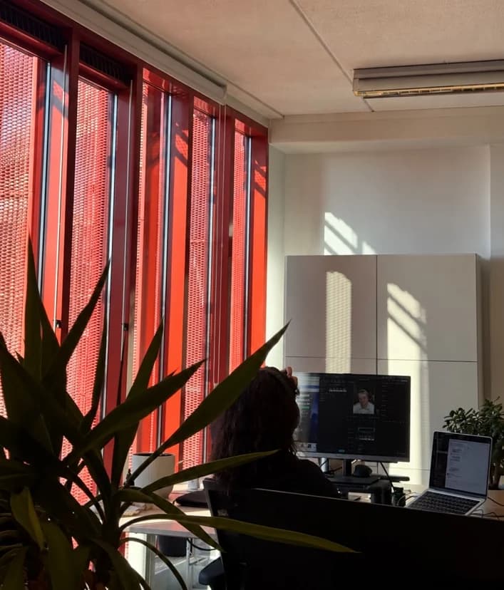 TNG Agency team member at work in the Amsterdam office, with sunlight coming through the red façade panels