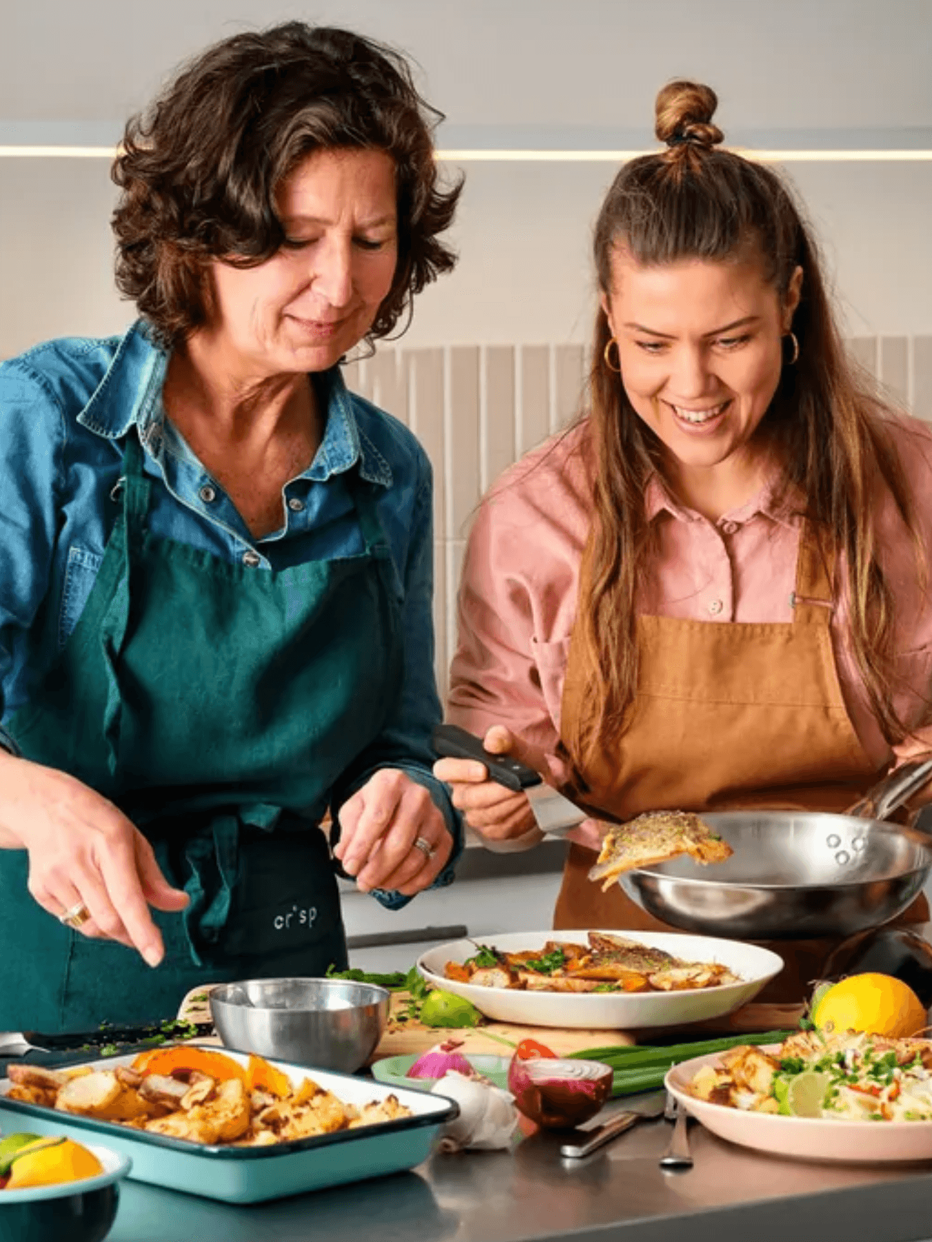 Twee vrouwen bereiden samen een maaltijd met vis en groenten in de keuken